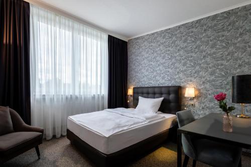 een slaapkamer met een bed, een stoel en een bureau bij Hotel Fischerhaus in Düsseldorf