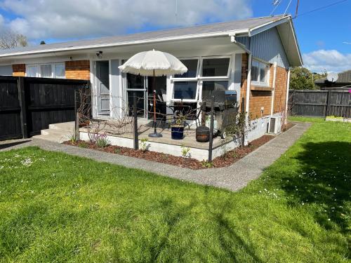 a small house with an umbrella on the front porch at Sunny 2bdrm home close to Hospital & Gardens in Hamilton