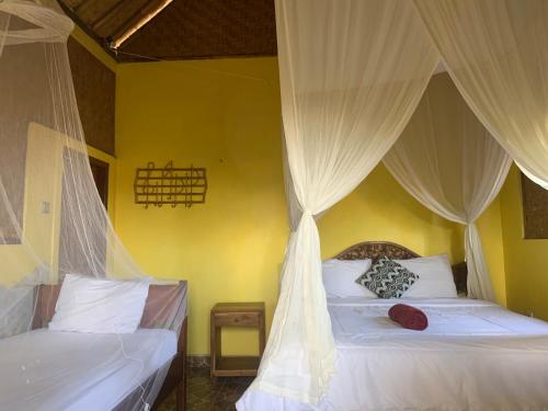 a bedroom with two beds with drapes at Jana's Homestay in Sidemen
