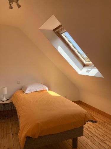 une chambre avec un lit et une lucarne dans l'établissement Maison au dessus de la plage 6 personnes, à Saint-Michel-en-Grève