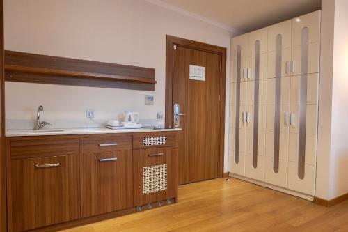 a kitchen with wooden cabinets and a sink and a door at Mimi Hotel Ankara in Ankara