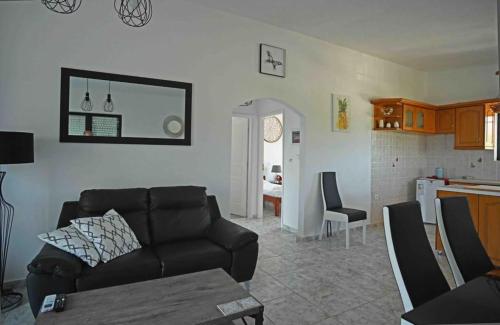 uma sala de estar com um sofá preto e uma cozinha em Άνετο διαμέρισμα για 4 με θέα em Erétria
