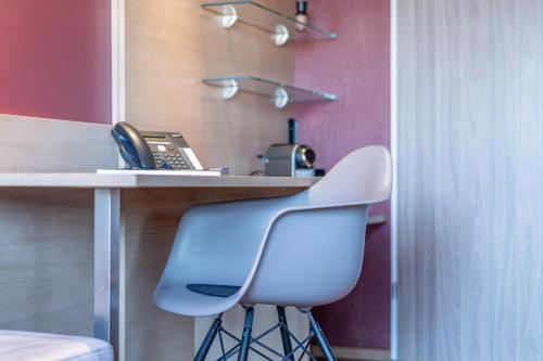 a desk with a phone and a white chair at hirschen dornbirn - das boutiquestyle hotel - skyrelax & wellness im rooftop in Dornbirn