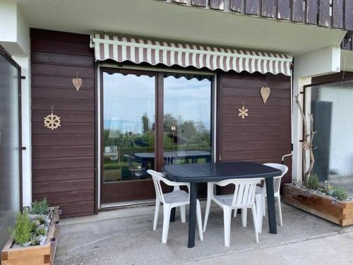 einen schwarzen Tisch und Stühle auf einer Terrasse in der Unterkunft Studio Myrtilles du Léman vue sur lac et montagne in Thollon