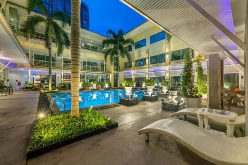 an exterior view of a building with a pool and palm trees at Qiu Hotel Sukhumvit SHA Plus in Bangkok