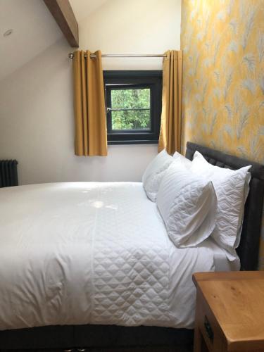 a bedroom with a bed with white sheets and a window at Tanners Lodge in Bewdley