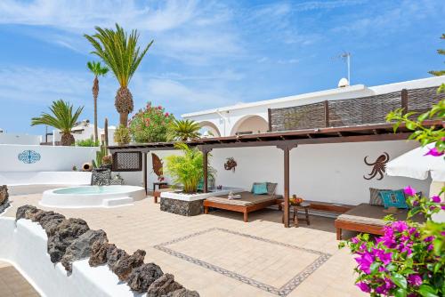 a house with a patio with palm trees at Villa Munay in Puerto del Carmen