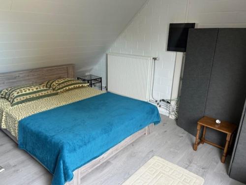a bedroom with a bed with a blue blanket and a television at Duivenboshuisje in Herzele