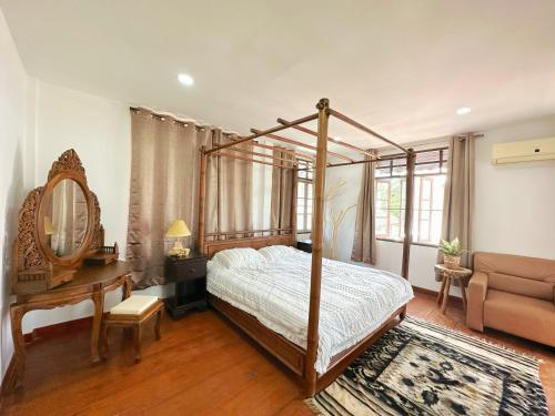 ein Schlafzimmer mit einem Himmelbett, einem Tisch und einem Sofa in der Unterkunft An‘s Home in Chiang Mai