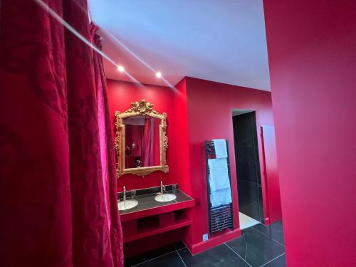 - une salle de bains rouge avec deux lavabos et un miroir dans l'établissement La Maison à Pan De Bois Chambre Napoléon III, à Vierzon