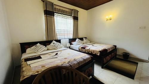 a room with two beds and a window at Thuring's Holiday Bungalow in Nuwara Eliya