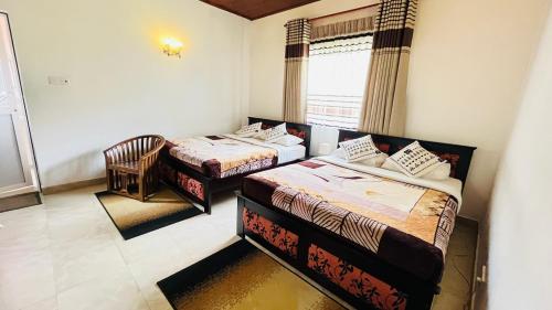 a room with two beds and a chair and a window at Thuring's Holiday Bungalow in Nuwara Eliya