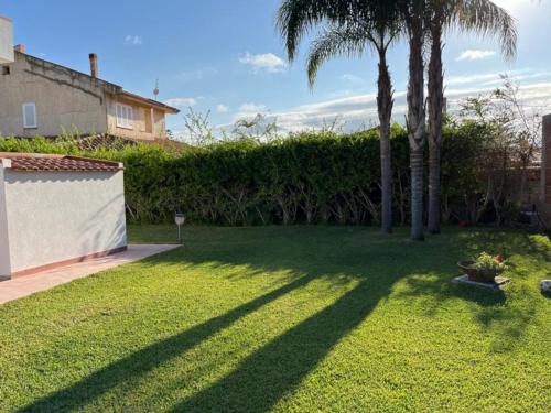 een tuin met palmbomen en een hek bij Villa Capri Holiday Home in Campofelice di Roccella