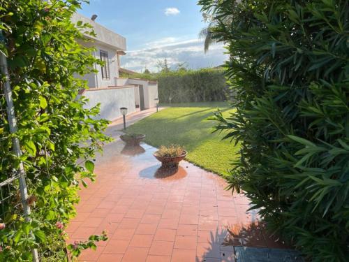 een tuin met een bakstenen loopbrug tussen twee struiken bij Villa Capri Holiday Home in Campofelice di Roccella