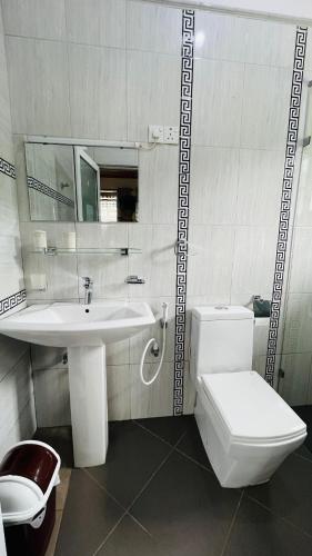 a white bathroom with a sink and a toilet at Thuring's Holiday Bungalow in Nuwara Eliya