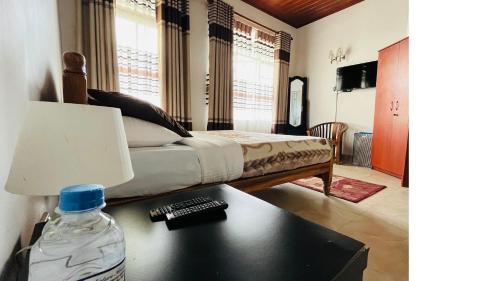 a bedroom with a bed and a bottle of water on a table at Thuring's Holiday Bungalow in Nuwara Eliya