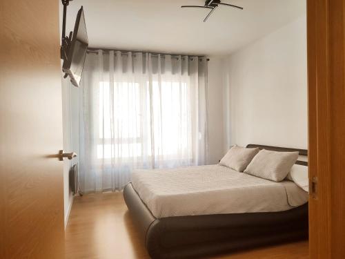 una camera con letto e finestra con tende bianche di milla sonsuites a O Milladoiro