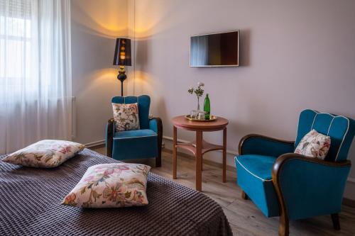 a room with two beds and two chairs and a table at Neptun Badacsony in Badacsonytomaj