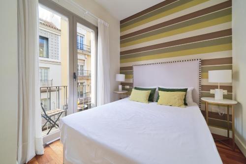 1 dormitorio con cama blanca y pared a rayas en Apartamento Premium en Centro Histórico, luminoso y acogedor en Málaga