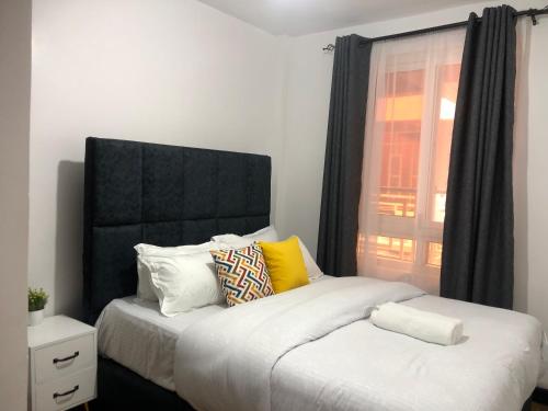 Un dormitorio con dos camas y una ventana. en Comfort Stay, en Nakuru