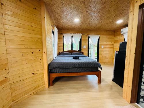 um quarto com uma cama num quarto de madeira em BaanSuan Marigold บ้านสวนมาลีโกลด์ em Ban Madua Chumphon