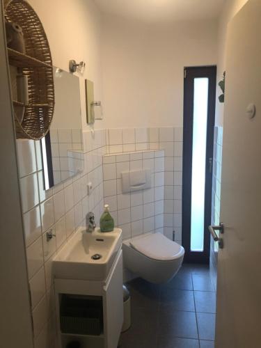 a white bathroom with a toilet and a sink at Alterwanderweg Haus in Hamburg