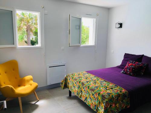 a bedroom with a bed and a chair and two windows at Villa Bella à 250m des plages in Biarritz