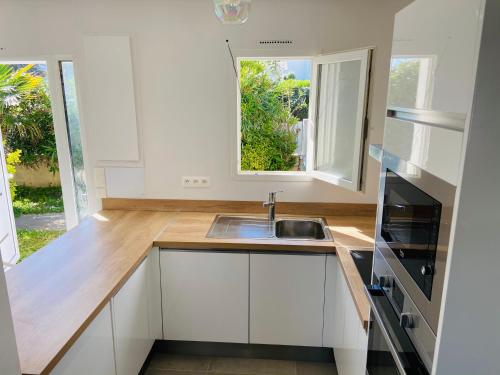 une cuisine avec des armoires blanches, un évier et une fenêtre dans l'établissement Villa Bella à 250m des plages, à Biarritz