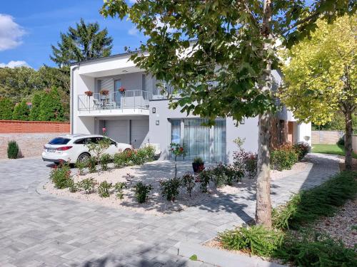 a white house with a car parked in front of it at Linden Apartman 105 - Adults Only in Mosonmagyaróvár