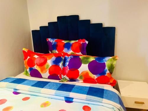 1 cama con cabecero azul y almohadas coloridas en Husein Accommodations en Ciudad del Cabo