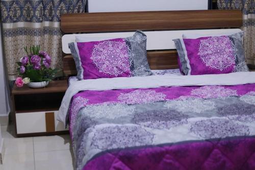 a bed with purple and gray sheets and pillows at Jeffston Court Apartments in Accra