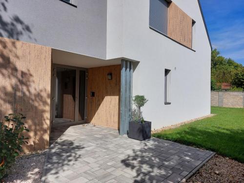 a white house with a potted plant on a patio at Linden Apartman 107 GLAMOUR in Mosonmagyaróvár