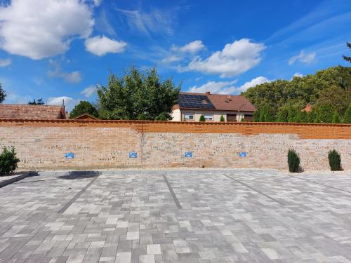 a brick wall with a house in the background at Linden Apartman 107 GLAMOUR in Mosonmagyaróvár