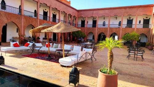 a courtyard with chairs and tables and an umbrella at Kasbah Caracalla in Aghmat