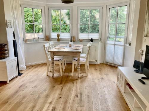 uma sala de jantar com mesa, cadeiras e janelas em Ferienwohnung Hafenglück, Villa Vilmblick em Lauterbach