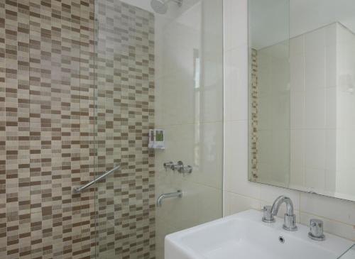 ein Bad mit einem Waschbecken und einer Dusche mit einem Spiegel in der Unterkunft Amaris Hotel Madiun in Madiun