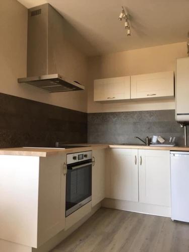 une cuisine avec des armoires blanches et un four à plaques de cuisson dans l'établissement Au 311, à Sainte-Cécile-Plage