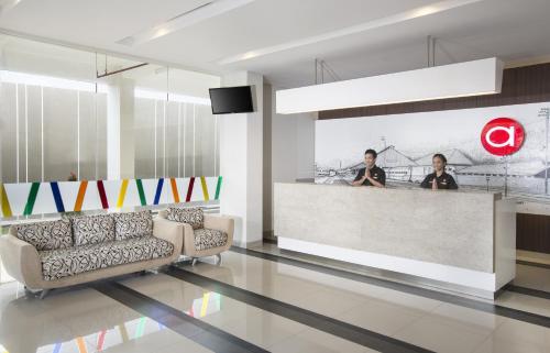 two men sitting at a counter in a lobby at Amaris Hotel Madiun in Madiun