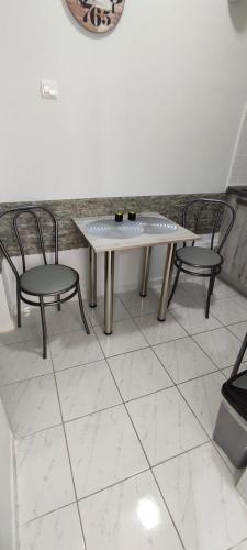 a table and two chairs on a white tile floor at ANASTASIA studio in Kavala