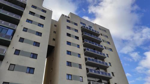 een groot wit appartementencomplex met blauwe ramen bij Home Residence in Piatra Neamţ