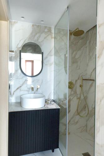 a bathroom with a sink and a glass shower at Civitas Suites Hotel in Rethymno Town