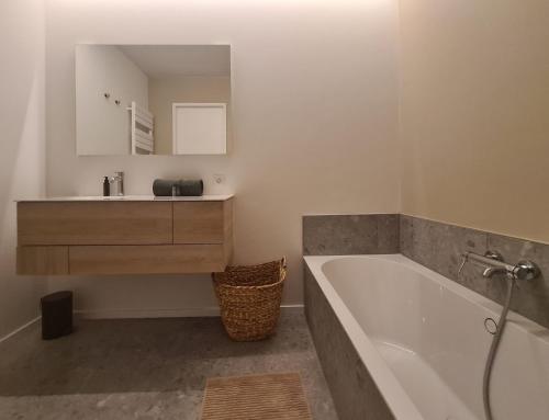 bagno con vasca, lavandino e specchio di Central Park Tower Sea View Residence with pool and gym a Ostenda
