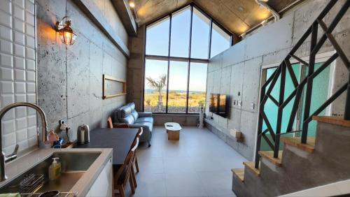 a kitchen and living room with a large window at Dalthor Pension in Jeju