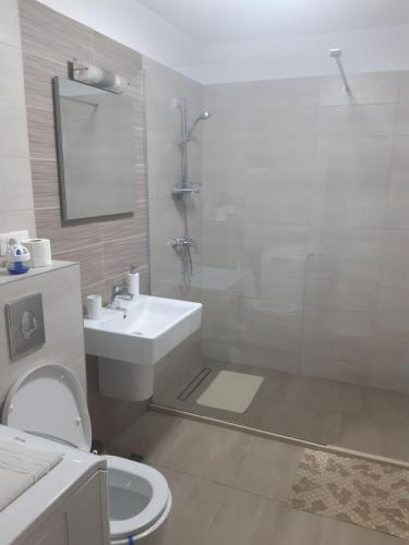 a white bathroom with a sink and a toilet at Apartament Marcel - Coresi Mall in Braşov