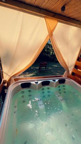 einen Whirlpool in einem Zelt mit Fenster in der Unterkunft Hébergement insolite dans une clairière in Beychac-et-Caillau