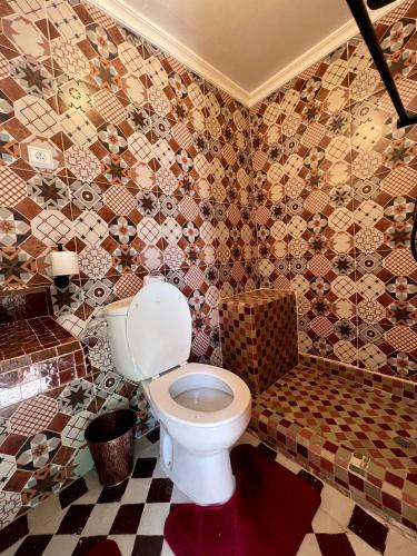a bathroom with a toilet and a tiled wall at Riad Al Nour in Marrakech