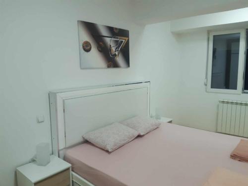 a bedroom with a white bed with a clock on the wall at Moonlight Pent in Skopje