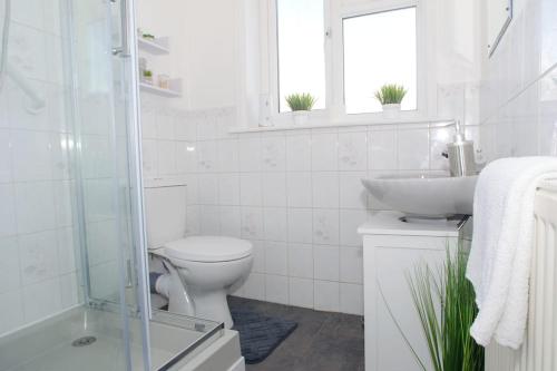 a white bathroom with a toilet and a sink at Vibrant 4 Bedroom House With Game Area & Garden in Southampton