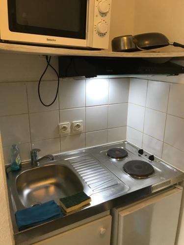 eine Küchentheke mit einer Spüle und einer Mikrowelle in der Unterkunft Coquet Studio PROCHE CENTRE in Straßburg
