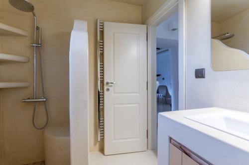 a bathroom with a shower and a white door at Mrs Kalis cottage in Andros